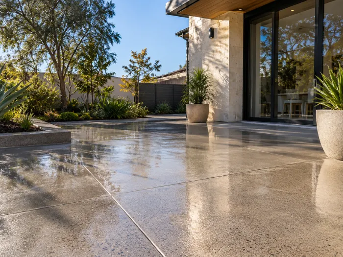 Sealed concrete patio flooring with a smooth finish beside a modern residential property